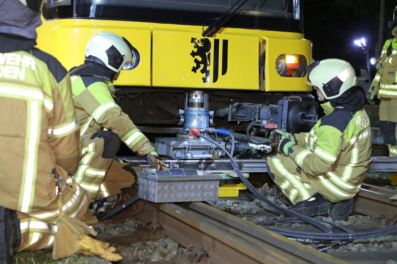 Einsatzkräfte heben eine Straßenbahn mit einem Hydraulikzylinder an