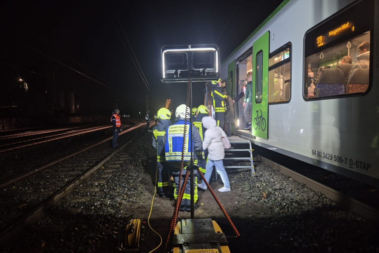 Feuerwehrangehörige und Bahnmitarbeiter helfen den Reisenden beim Ausstieg aus dem Zug